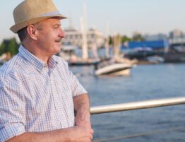Man standing by a waterfront railing, looking out over boats at a marina during daylight