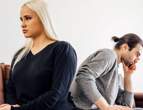 Couple sitting apart on a couch reflecting tension during divorce and long-term financial decisions