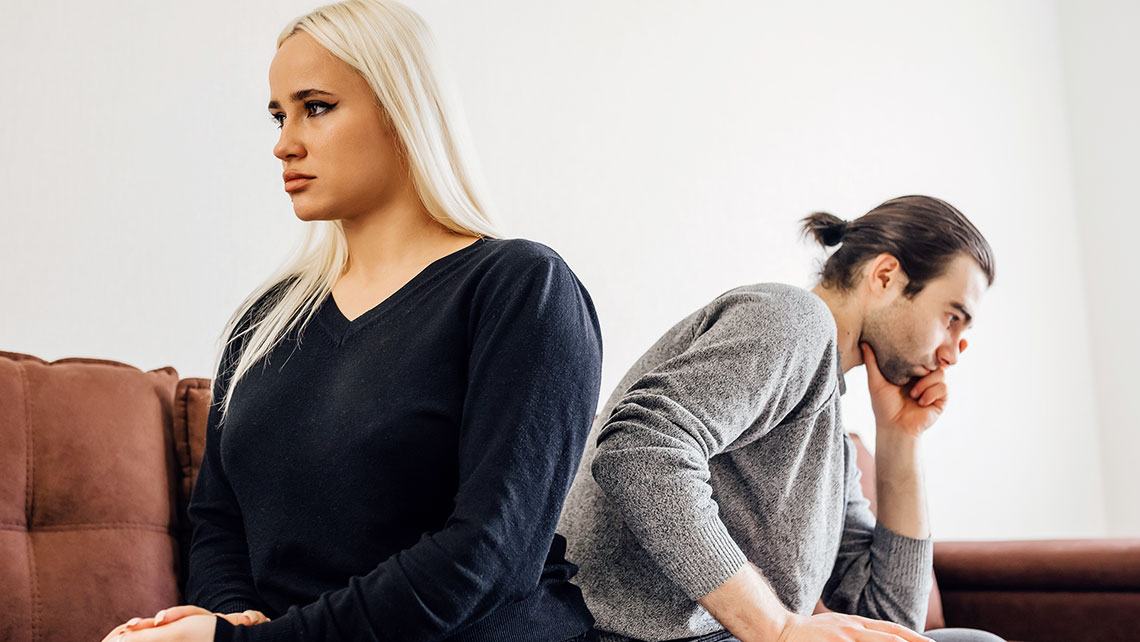 Couple sitting apart on a couch reflecting tension during divorce and long-term financial decisions