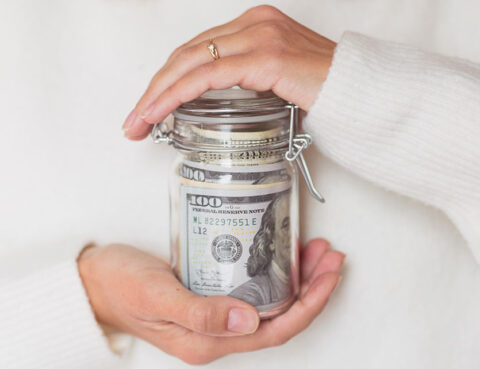 Hands holding a jar of money representing saving and financial planning after divorce