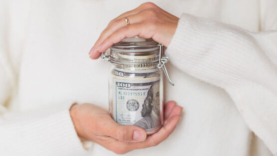 Hands holding a jar of money representing saving and financial planning after divorce