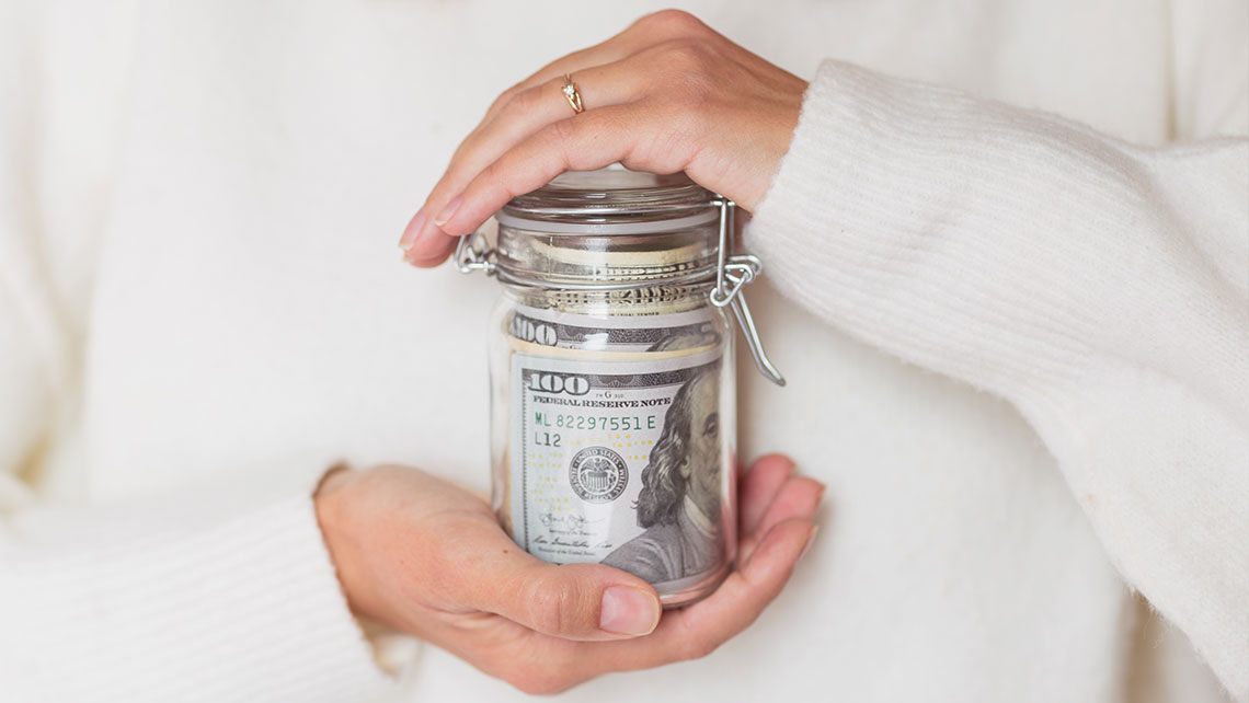 Hands holding a jar of money representing saving and financial planning after divorce