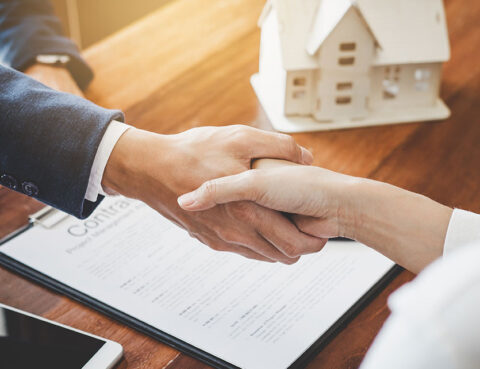 Two people shaking hands over a contract representing divorce settlement agreement and asset division