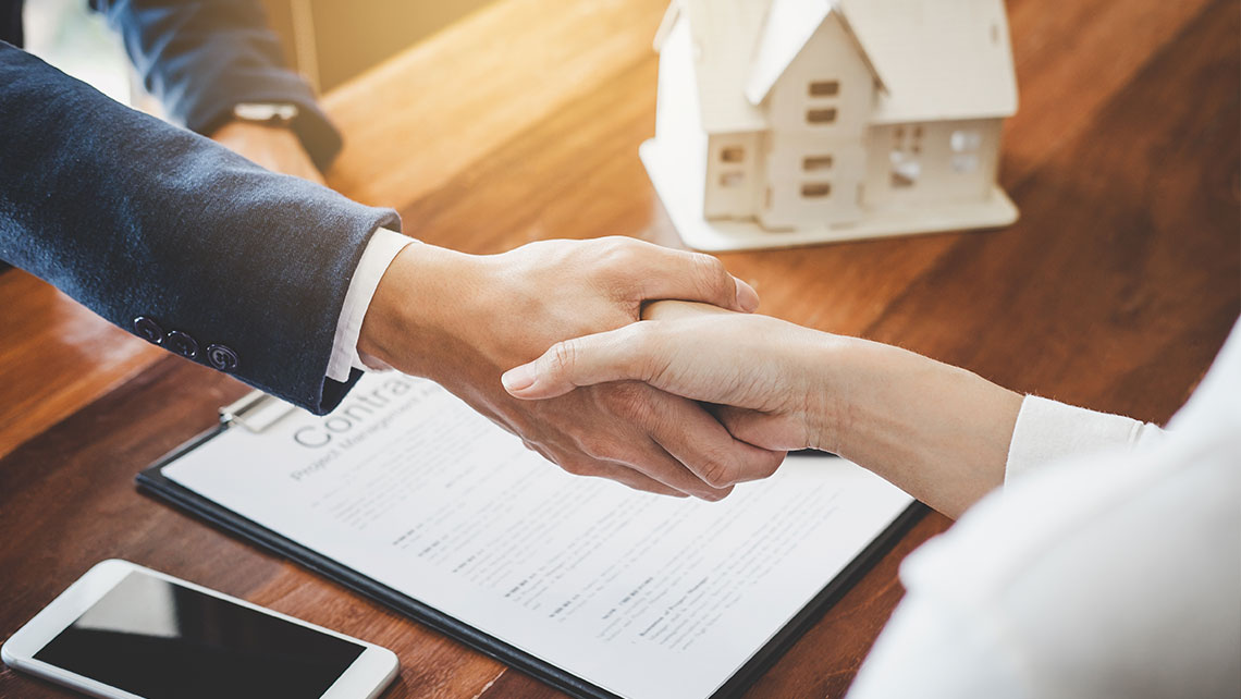 Two people shaking hands over a contract representing divorce settlement agreement and asset division