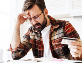 Man reviewing bills and holding a credit card while stressed about divorce finances and financial decisions