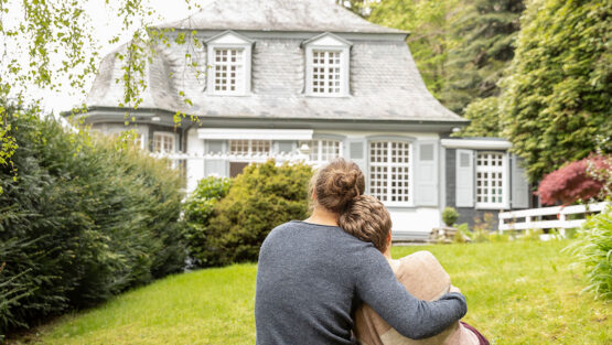 Person sitting with a child looking at a family home while considering housing decisions during divorce.